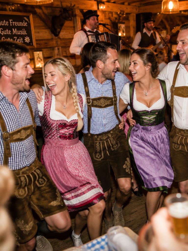 Friends in Tyrolean dress dancing arm in arm to live music